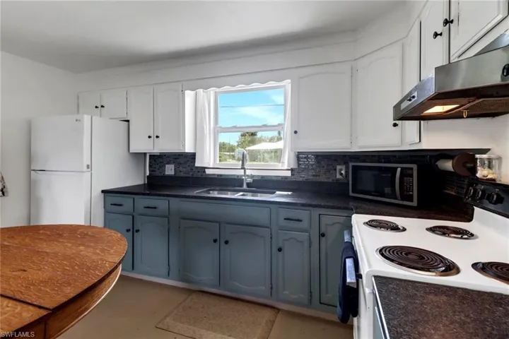Kitchen featuring white cabinetry, white appliances, sink, and decorative backsplash