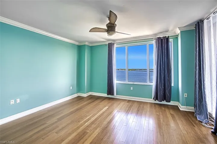 Empty room with crown molding, wood-type flooring, and ceiling fan
