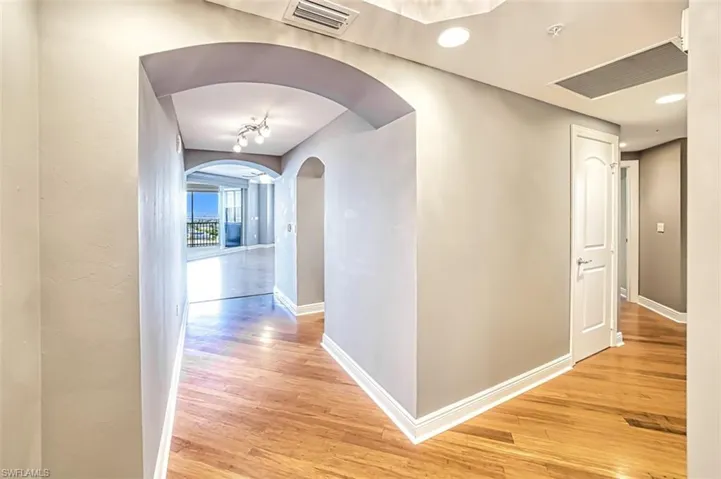 Corridor with light wood finished floors and arched walkways