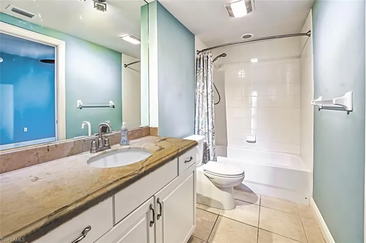 Full bath with vanity, shower / bath combination with curtain, and light tile patterned flooring