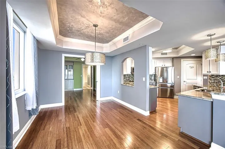 Unfurnished dining area featuring crown molding, a raised ceiling, and dark wood-style floors