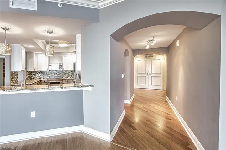 Kitchen with pendant lighting, white cabinetry, backsplash, stone countertops, and hardwood / wood-style floors