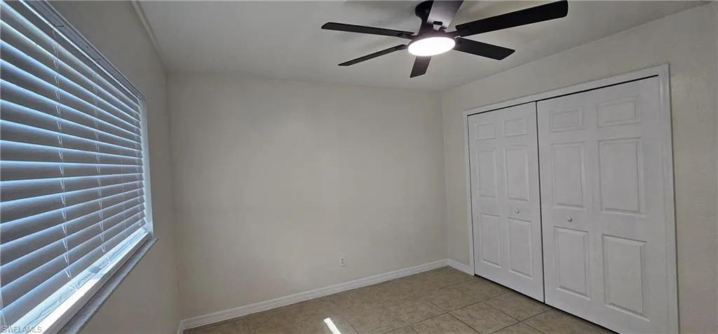 Guest bedroom featuring light tile patterned floors, a ceiling fan, and a closet