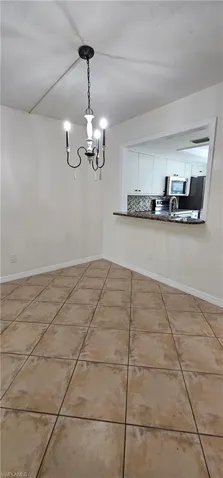 Unfurnished dining area with a chandelier and light tile patterned floors