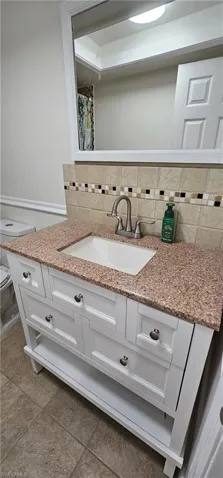 Full bathroom with vanity, decorative backsplash, and a shower with curtain