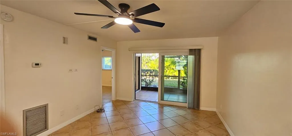Living room with light tile patterned floors and a ceiling fan