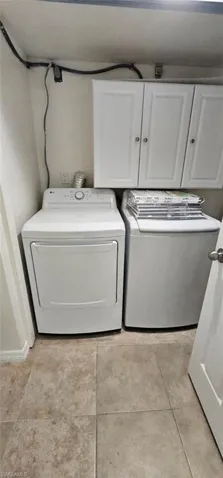 Washroom featuring cabinet space, separate washer and dryer, and light tile patterned floors