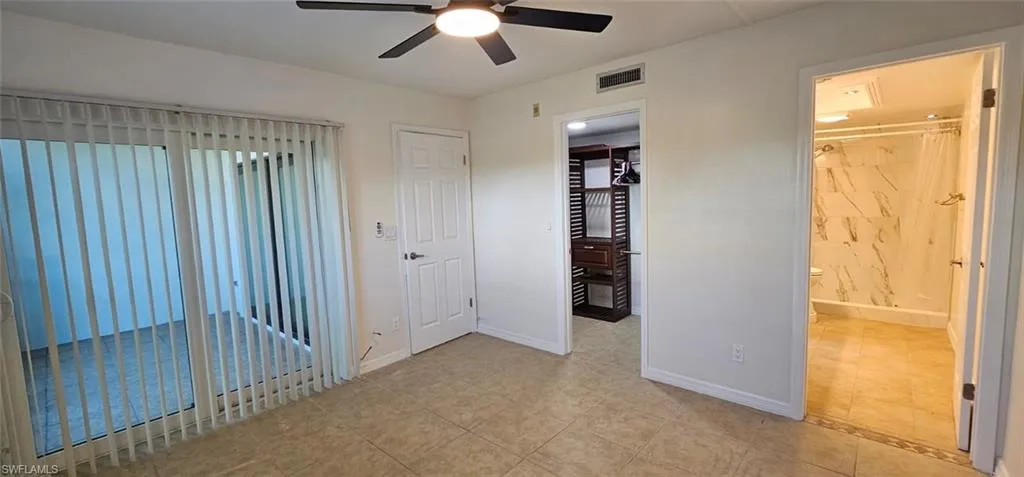 Master bedroom with ensuite bathroom, a ceiling fan, and light tile patterned floors