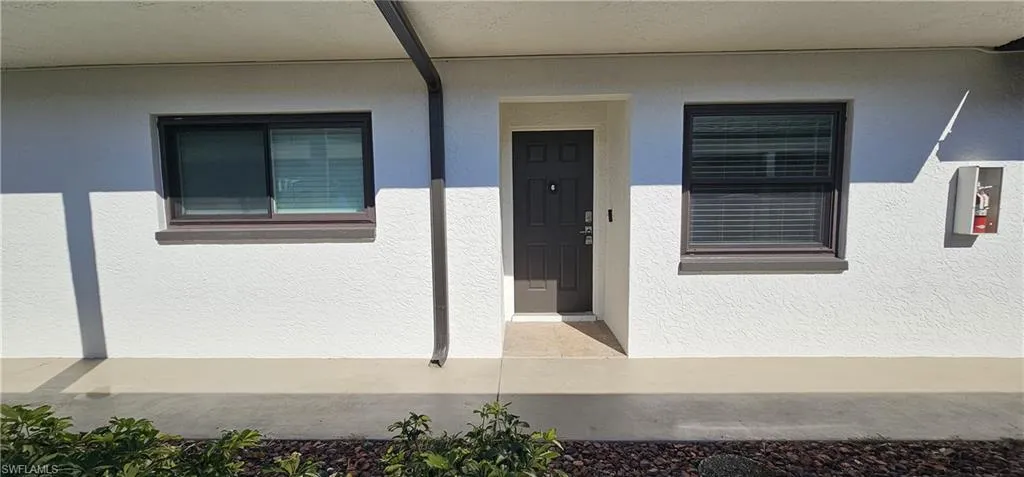 Entrance to property featuring covered porch and stucco siding