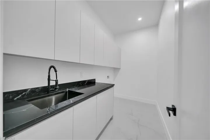 Laundry room with cabinet space, recessed lighting, hookup for a washing machine, and light marble finish flooring