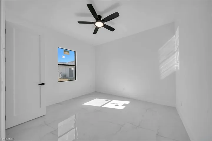 Unfurnished room with light marble finish floors and a ceiling fan
