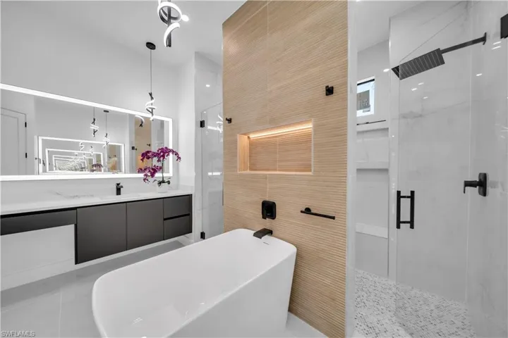 Full bath with a marble finish shower, vanity, and a freestanding tub