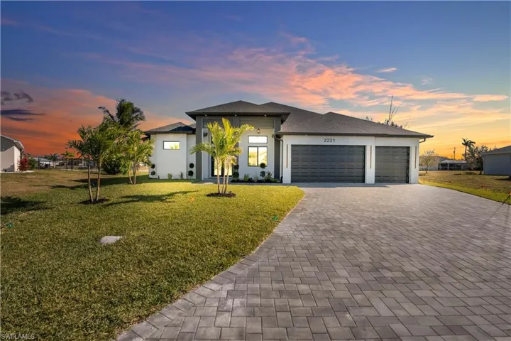 Prairie-style house with a lawn, an attached garage, decorative driveway, stucco siding, and roof with shingles
