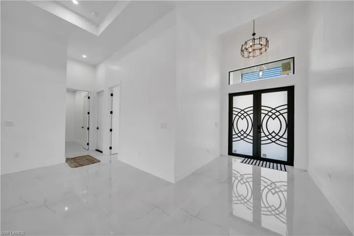 Foyer with a high ceiling, marble tiled flooring, french doors, and suspended lighting