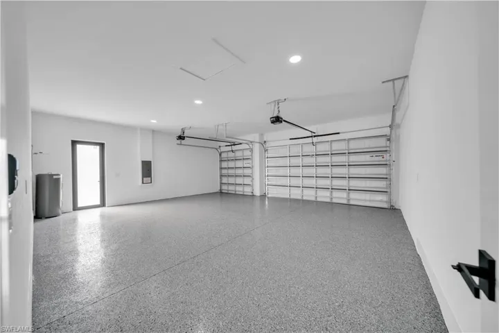 Garage featuring water heater, electric panel, and recessed lighting