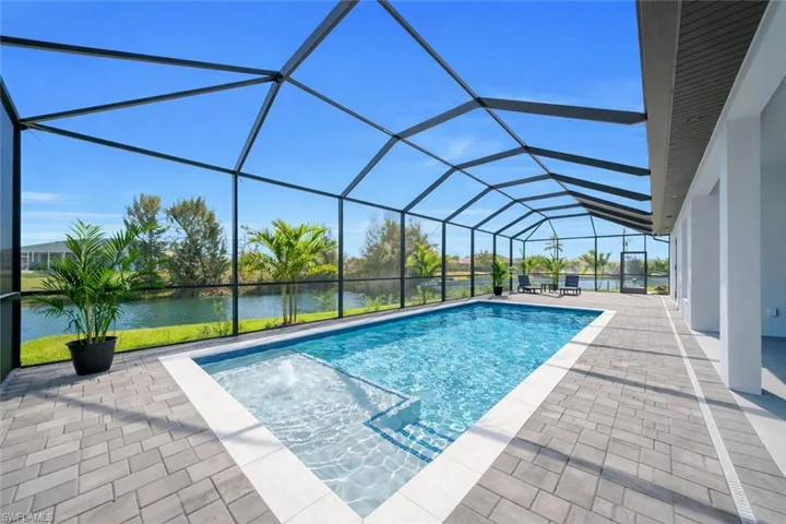 Outdoor pool with a sunroom, a patio area, glass enclosure, and a water view
