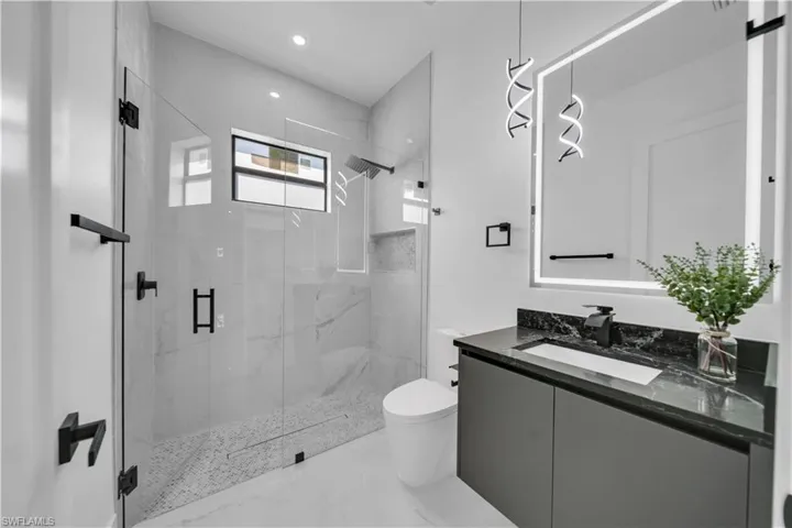 Full bath with a marble finish shower, vanity, and recessed lighting