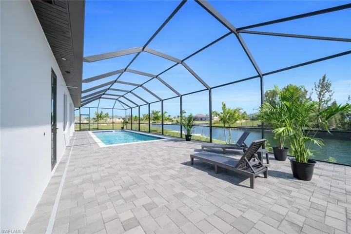 Swimming pool featuring a sunroom, a patio area, glass enclosure, and a water view