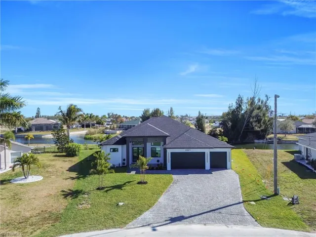 View of front of home featuring an attached garage, decorative driveway, a front lawn, and a shingled roof