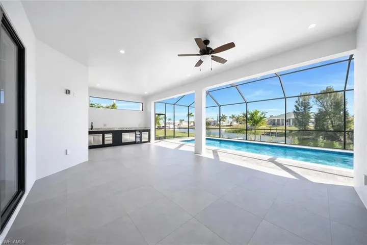 Outdoor pool with a sunroom, glass enclosure, a patio, and a water view
