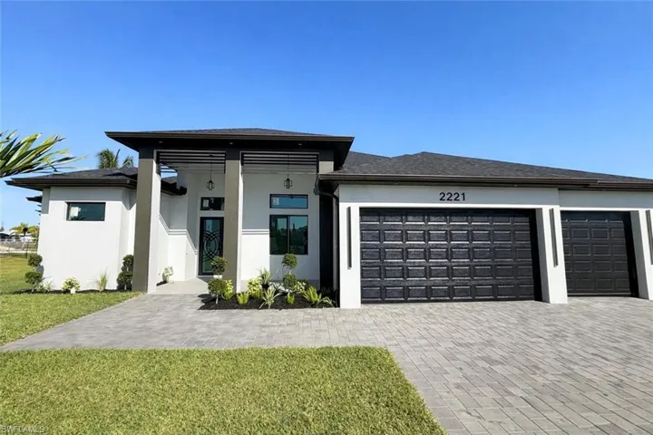 Prairie-style home with stucco siding, a garage, a front lawn, and decorative driveway
