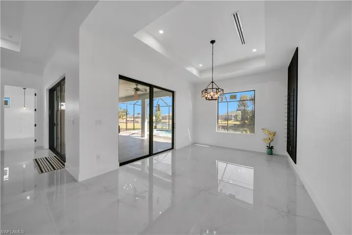 Unfurnished dining area with light marble finish floors, a raised ceiling, suspended lighting, and ceiling fan