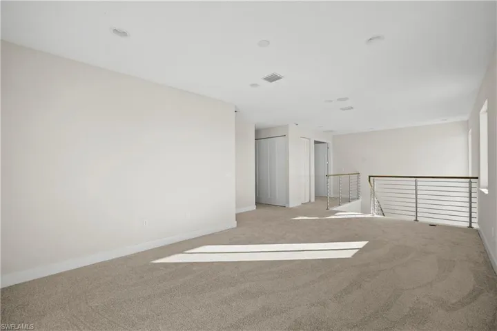 Carpeted loft or flex space with recessed lighting