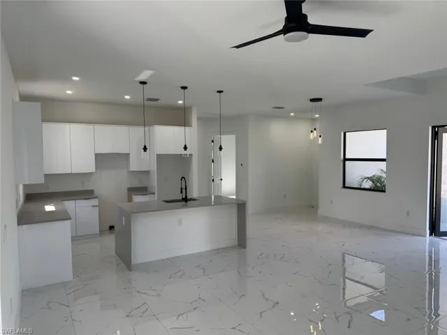 Kitchen featuring a sink, open floor plan, recessed lighting, white cabinetry, and a kitchen island with sink