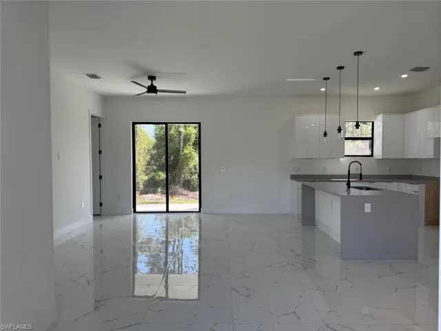 Kitchen featuring a center island with sink, open floor plan, marble finish floor, and a sink