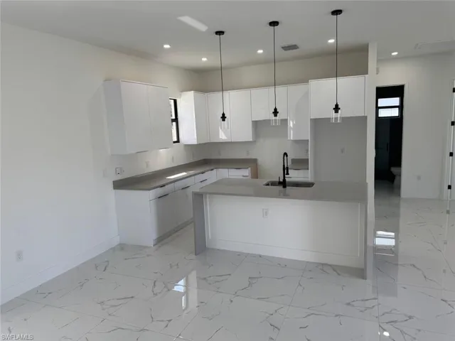 Kitchen with visible vents, marble finish floor, a center island with sink, a sink, and recessed lighting