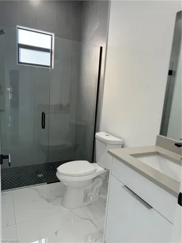 Bathroom with vanity, an enclosed shower, and toilet