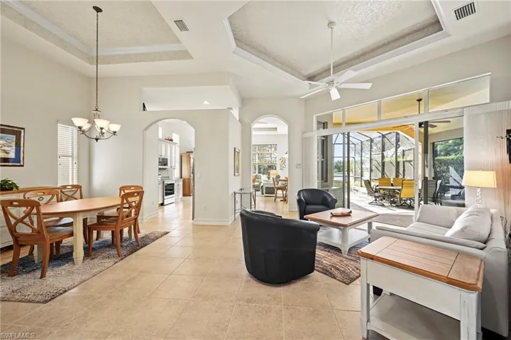 Living area with a tray ceiling, plenty of natural light, a sunroom, and a textured ceiling