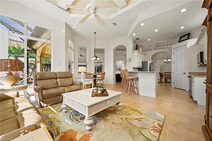 Living room with coffered ceiling, arched walkways, recessed lighting, a ceiling fan, and a chandelier