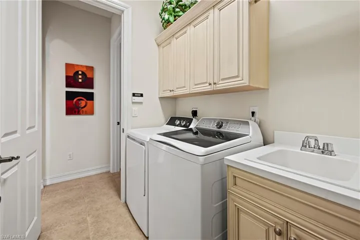 Laundry room with separate washer and dryer, light tile patterned floors, and cabinet space