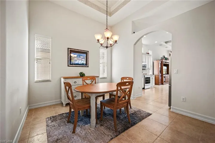 Dining space with arched walkways, a chandelier, and a towering ceiling