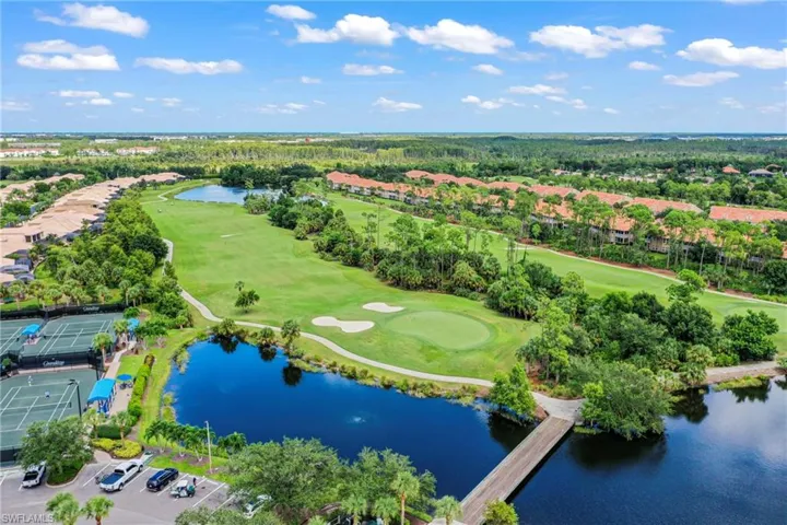Aerial view of residential area featuring a golf course and a nearby body of water
