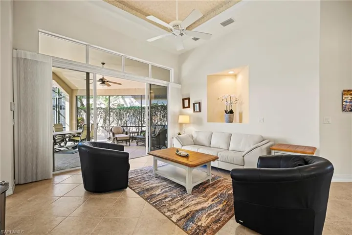 Living room featuring a sunroom, a ceiling fan, light tile patterned floors, and a high ceiling