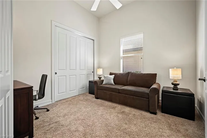 Carpeted office space featuring a ceiling fan and baseboards