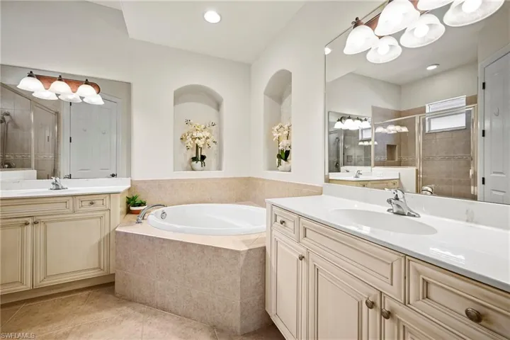Bathroom with two vanities, a bath, a stall shower, and light tile patterned floors