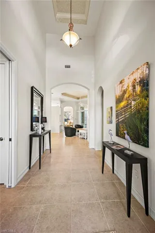 Hall featuring a high ceiling, a raised ceiling, and arched walkways