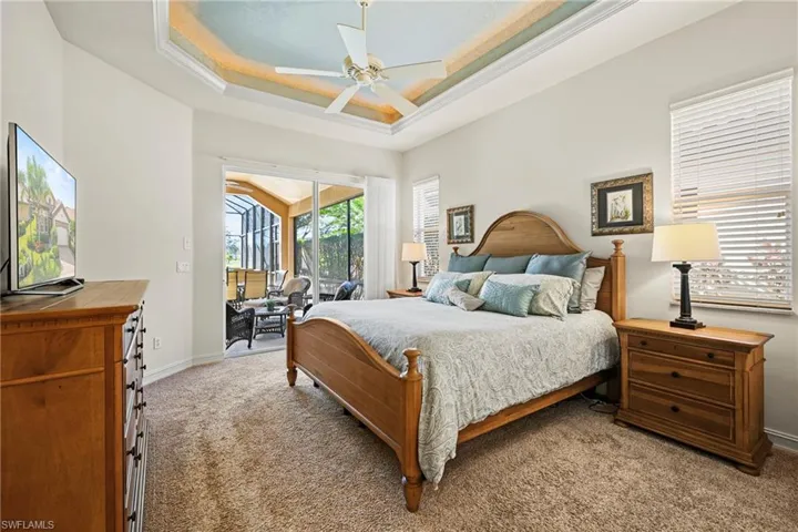 Carpeted bedroom featuring a tray ceiling, ceiling fan, and access to outside