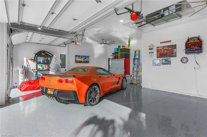 Garage with a garage door opener, electric panel, and baseboards