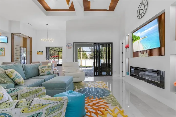 Living room with marble finish floor, beamed ceiling, a high ceiling, and an inviting chandelier