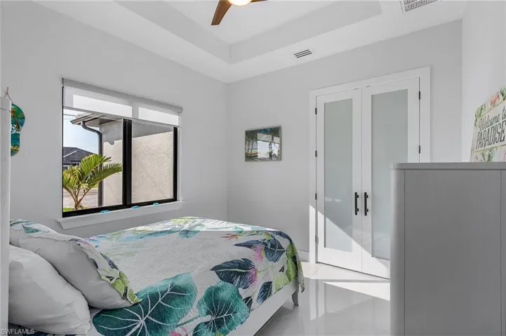 Bedroom featuring a ceiling fan, a tray ceiling, french doors, and visible vents