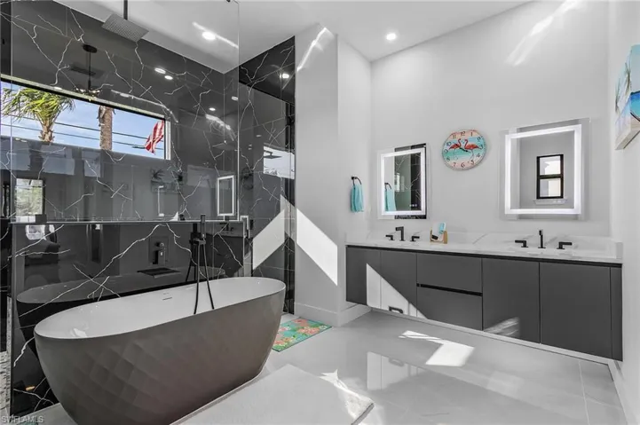 Bathroom featuring double vanity, a marble finish shower, a freestanding bath, a sink, and recessed lighting