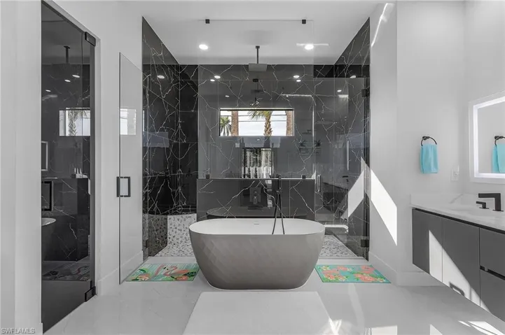 Full bath featuring a freestanding bath, a marble finish shower, vanity, and recessed lighting