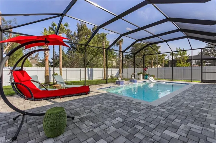 View of swimming pool featuring glass enclosure, a patio area, a fenced backyard, and a fenced in pool