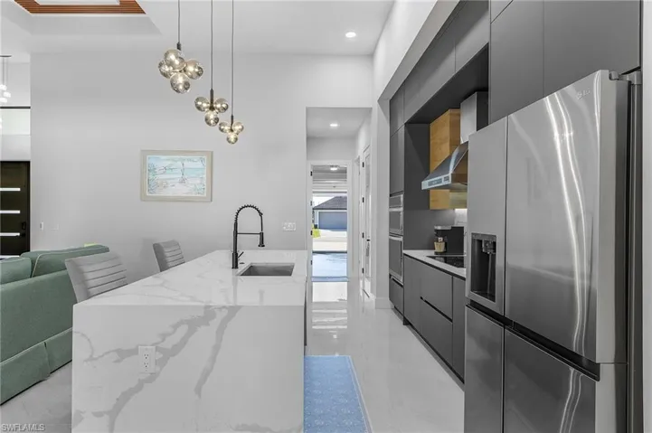 Kitchen with a sink, wall chimney exhaust hood, stainless steel refrigerator with ice dispenser, and modern cabinets