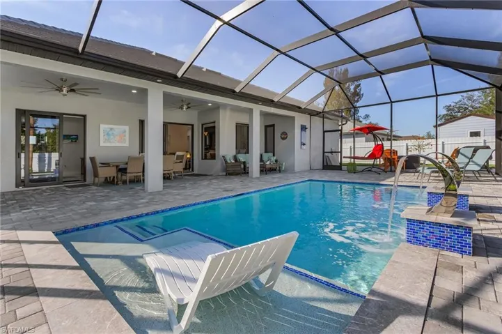 Outdoor pool featuring ceiling fan, a lanai, fence, a patio area, and outdoor lounge area