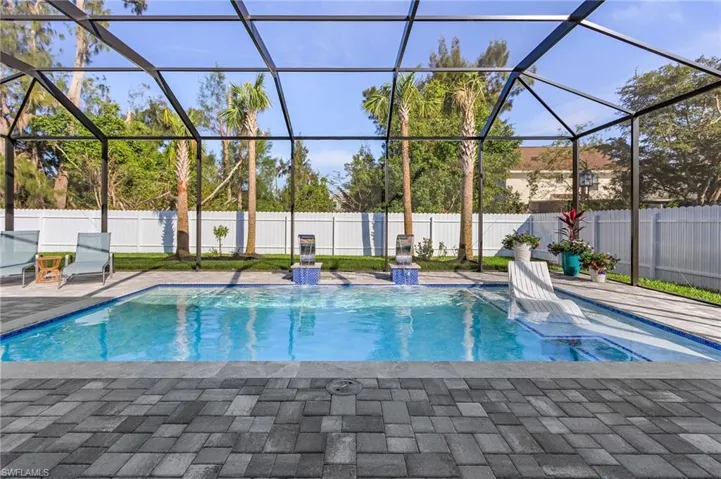 View of pool featuring glass enclosure, a patio area, a fenced backyard, and a fenced in pool